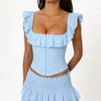 Studio Ruban light blue U-neck embroidered eyelet vest with ruffle trim and hook-and-eye front closure.