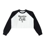 Studio Ruban white crop sweatshirt with black raglan sleeves and raw hem. Features gothic text "Hustlin all my LIFE." and a bee graphic.