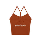 Studio Ruban women's rust orange spaghetti strap yoga sports bra with cutout detail and white logo.